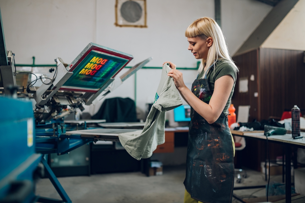 Printing,workshop,female,worker,taking,off,machine,silkscreen,printed,t Shirt.